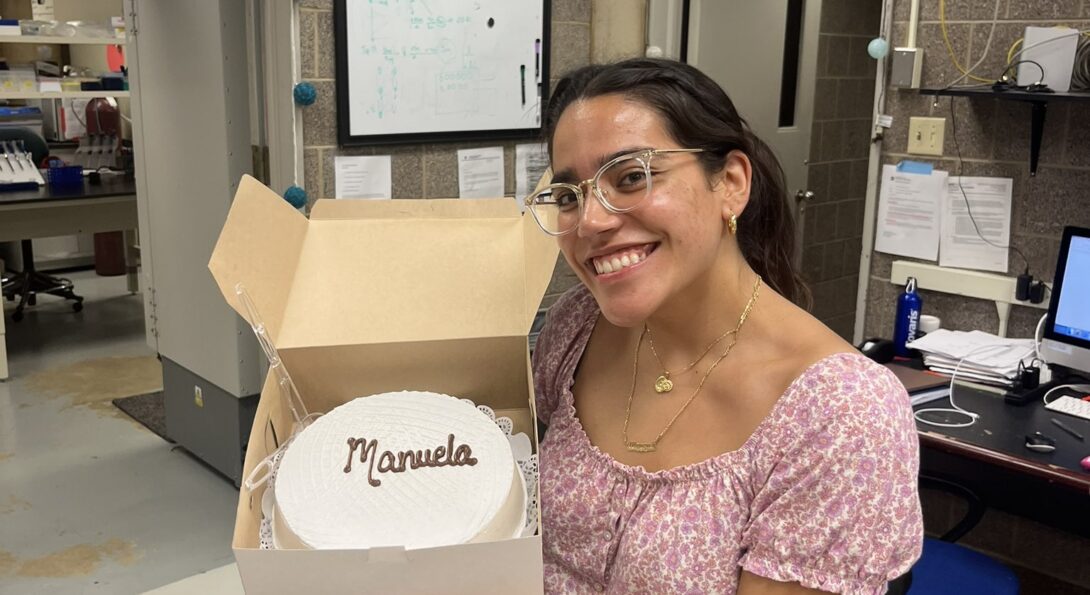 Image of young woman smiling holding a cake that reads, 
